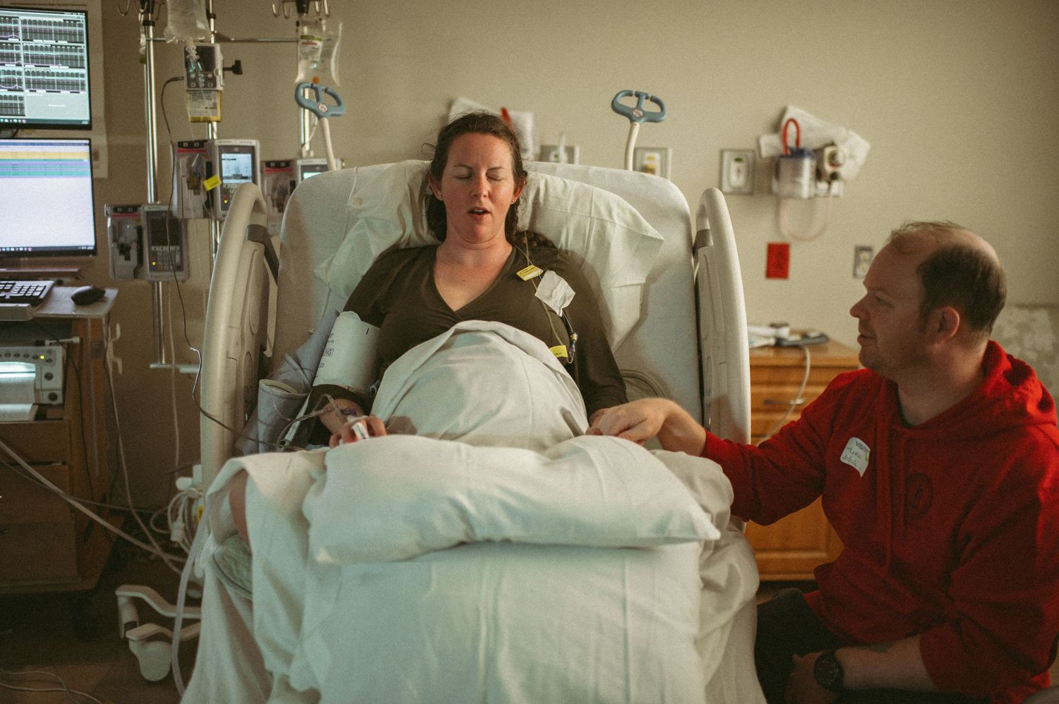 Expecting mother in hospital bed with supportive partner beside her in a Norfolk labor and delivery room.