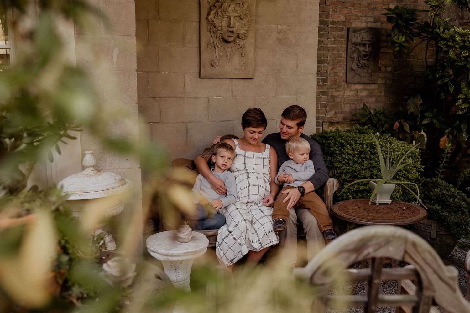 Expecting family posing during their maternity session in a Portsmouth secret garden.