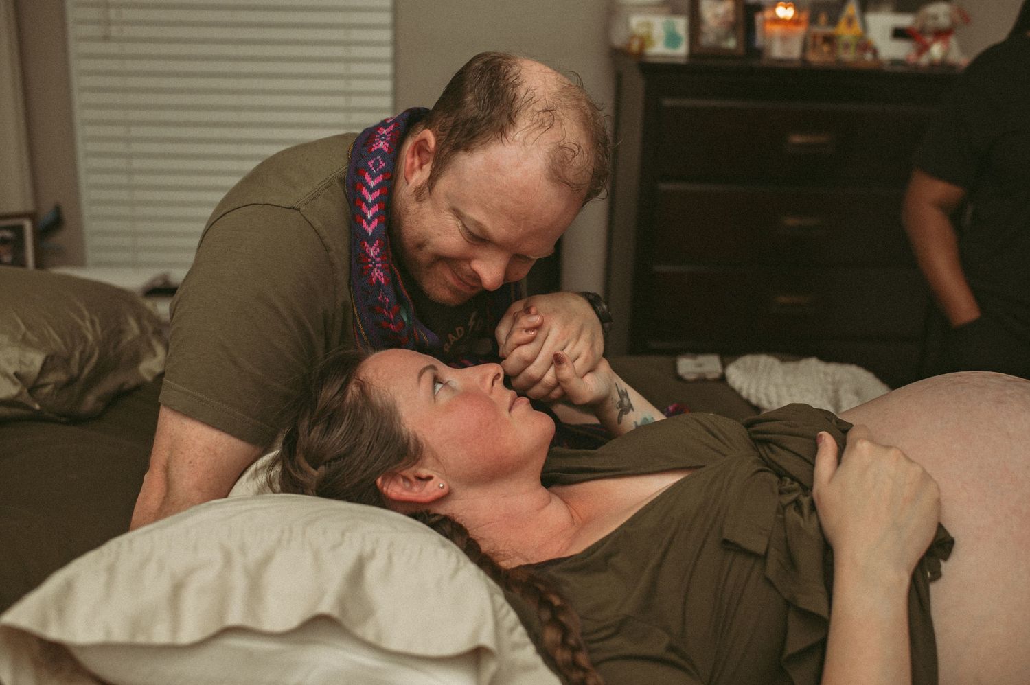 Husband and wife share a moment while their midwife breaks her water so that their baby could get closer to coming earth side.