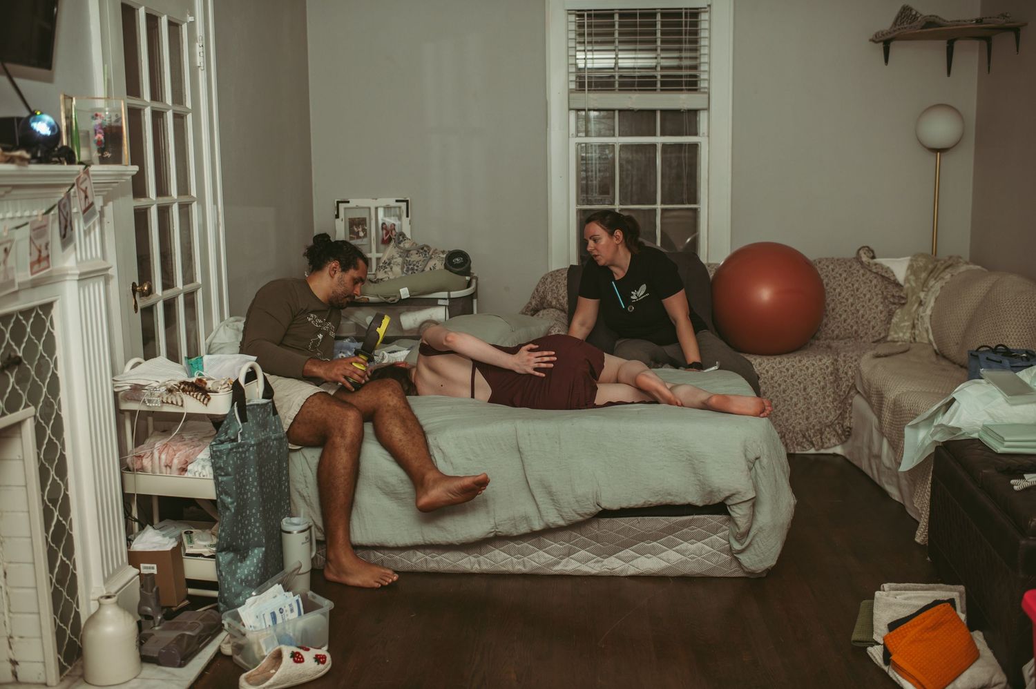 Hampton Roads, Virginia midwife student checking in on the expecting couple while laboring mom lays on the bed.