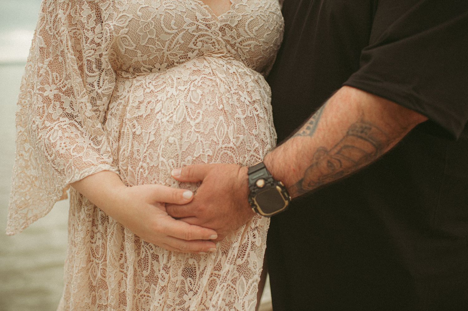 Expecting father holding his wife's belly during their maternity session at a local park in Gloucester, Virginia.