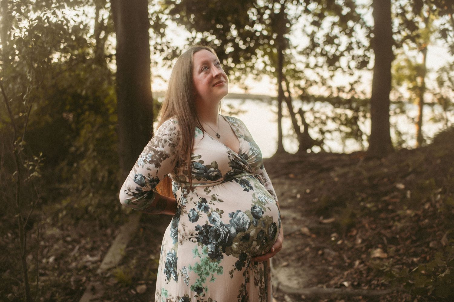 Expecting Suffolk mom posing in the woods near water for her maternity session.