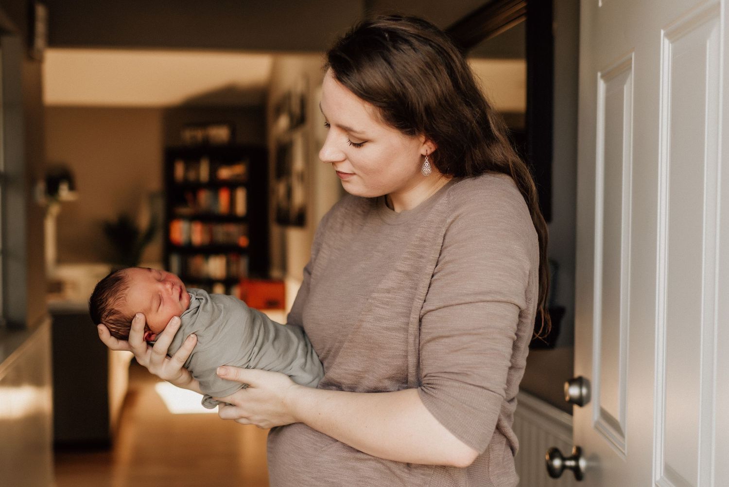 Virginia Beach mom holding baby boy posing at their front door during a newborn session.