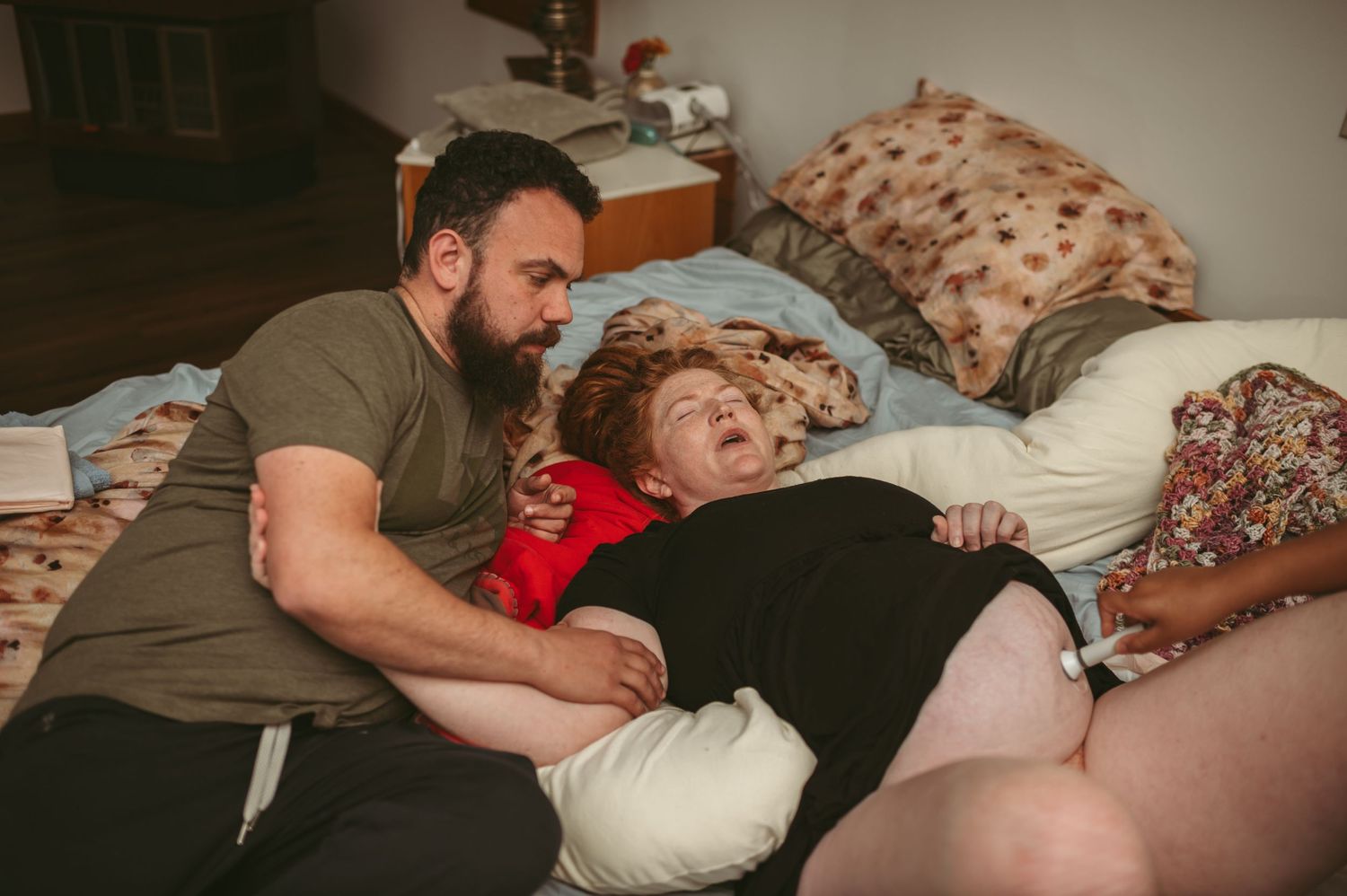Husband supporting his wife through intense contractions while laying in their bed at their Newport News, Virginia home.