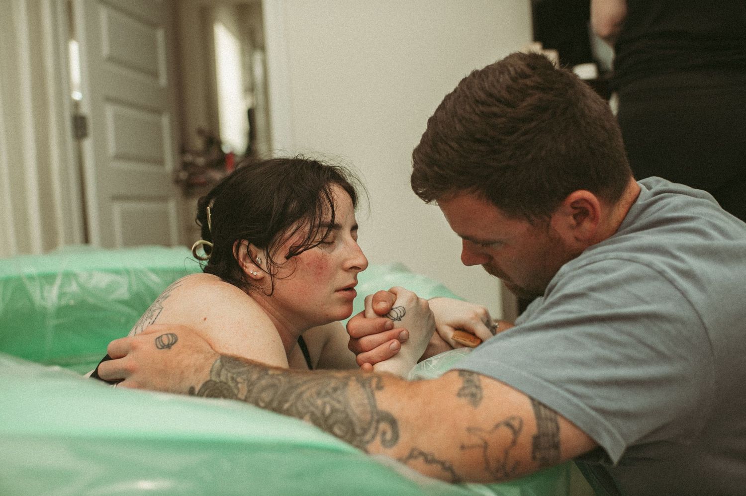 Expecting dad holds expecting mom's hands while she labors in a birthing pool in their Suffolk, Virginia home.