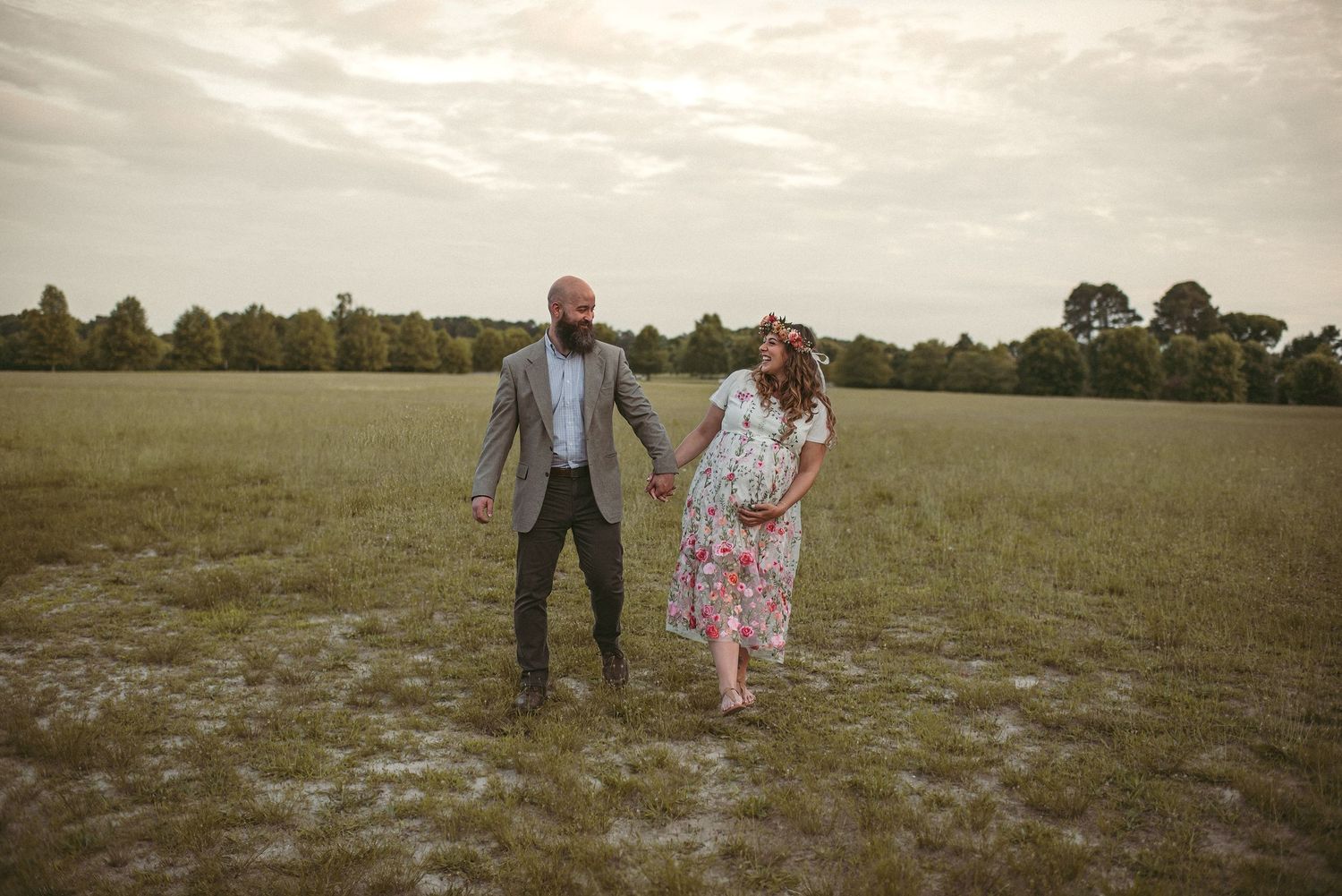 Expecting couple strolling in a open field at a park in Smithfield, Virginia.
