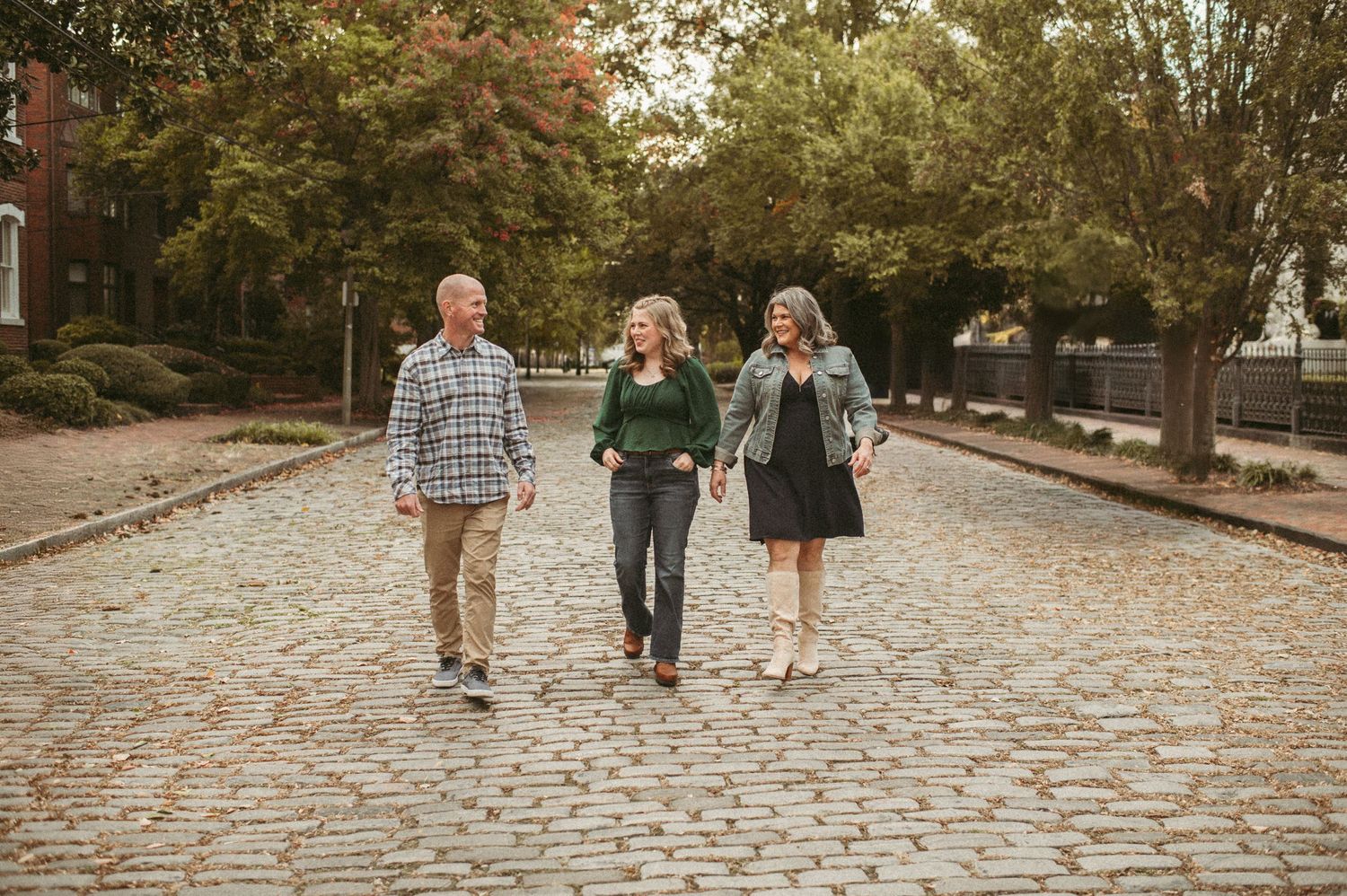 Virginia family walks down a cobblestone street  in the Freemason district of Norfolk with trees and buildings in the background.