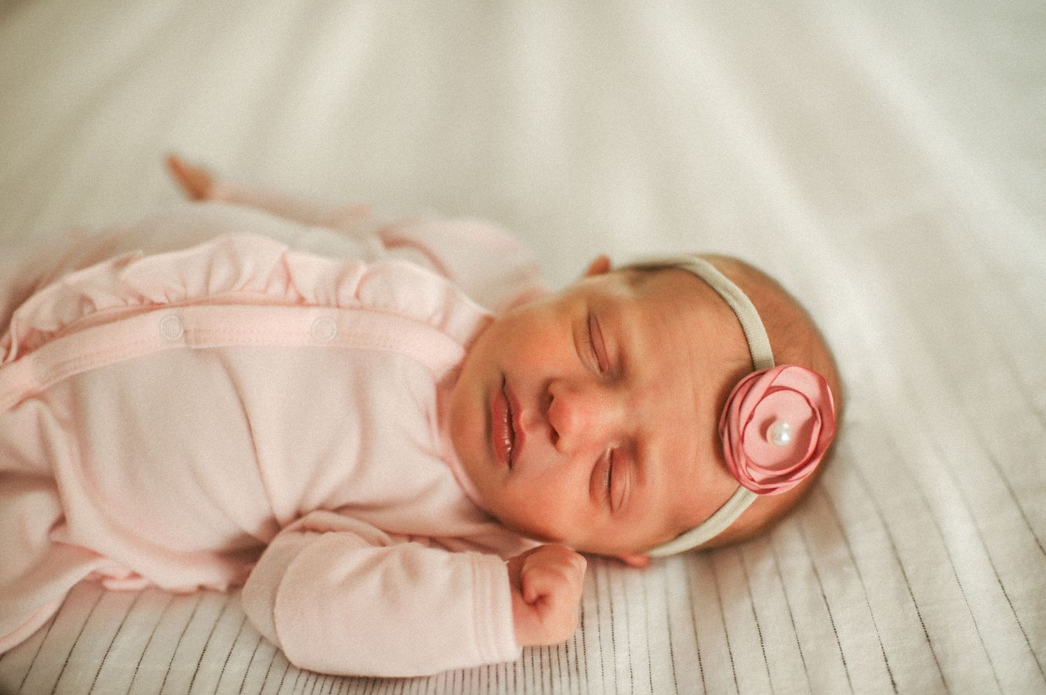 Baby girl laying on a bed during a lifestyle newborn session in a Suffolk, Virginia home.