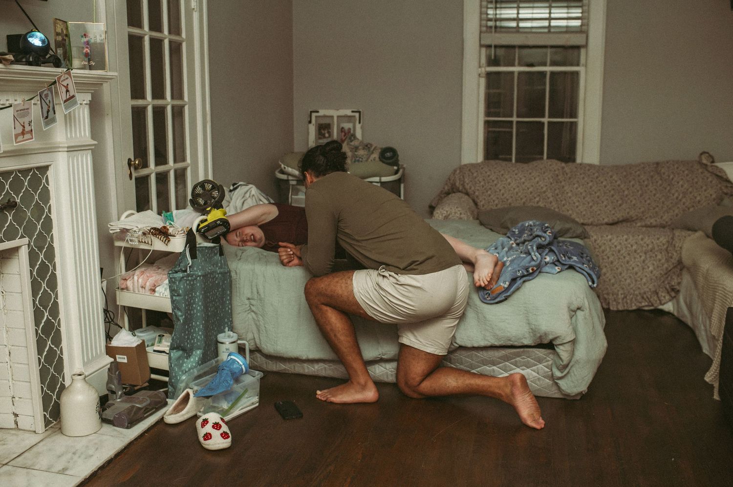 Expecting dad supporting expecting mom in their Portsmouth, Virginia home while she labors on a bed in their living room.