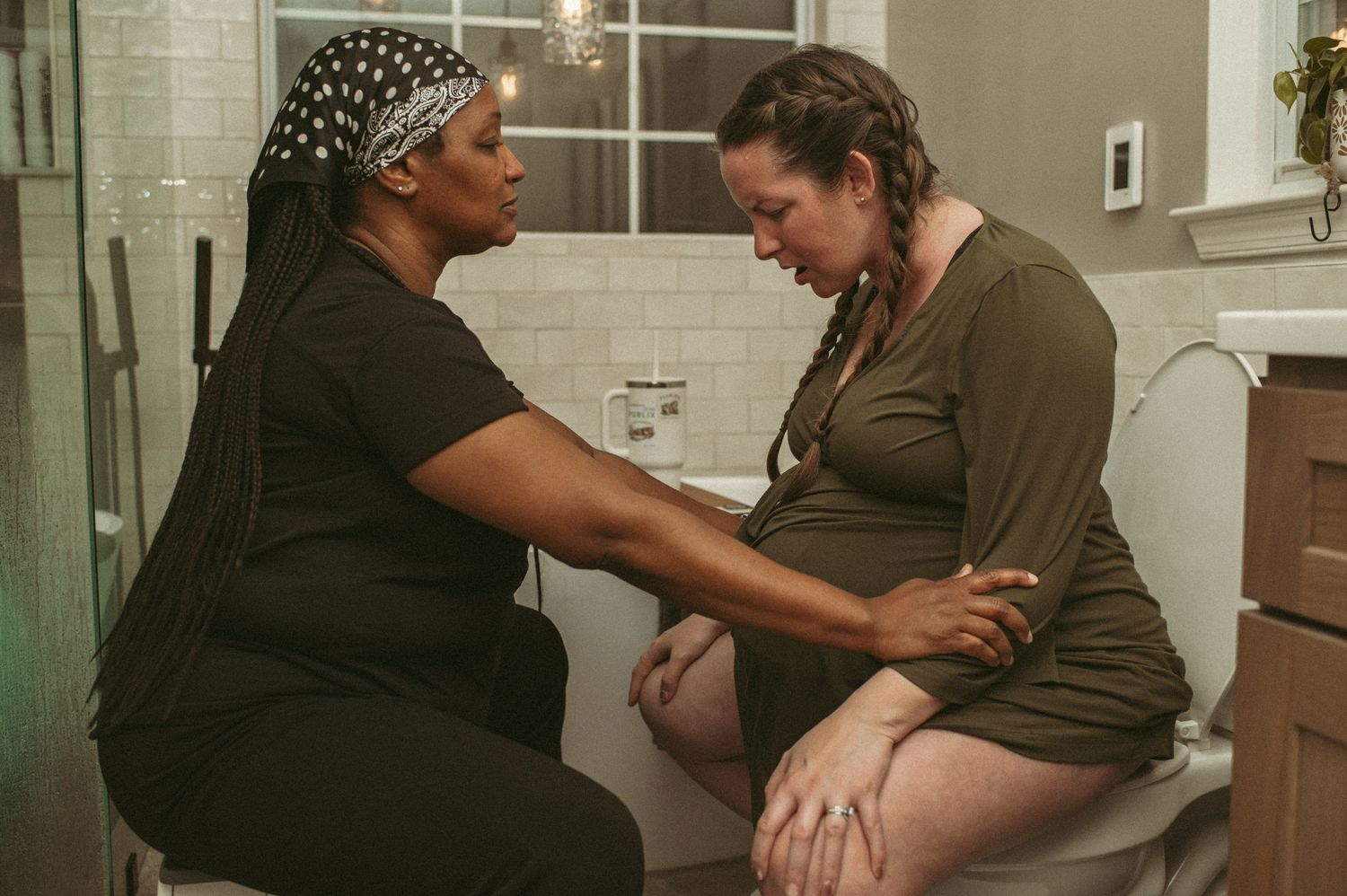 Labor doula supporting her client while she labors on the toilet in her bathroom.