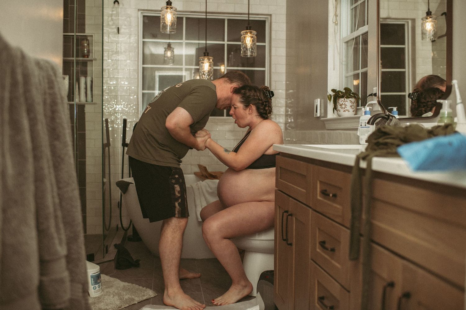 Expecting father supports his laboring wife in their home in Virginia.