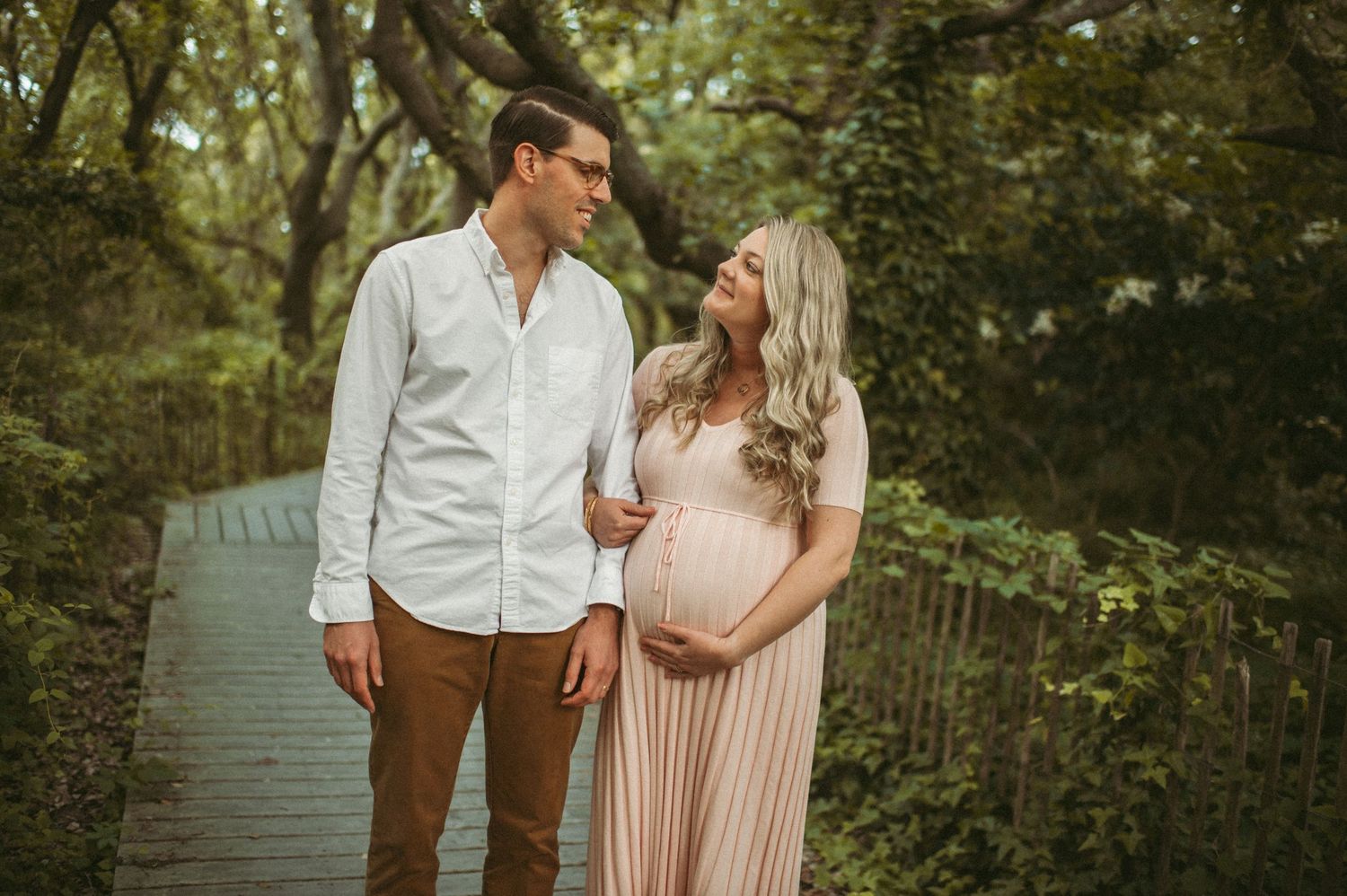 Expecting couple walking down a beach access in Virginia Beach during their maternity session.