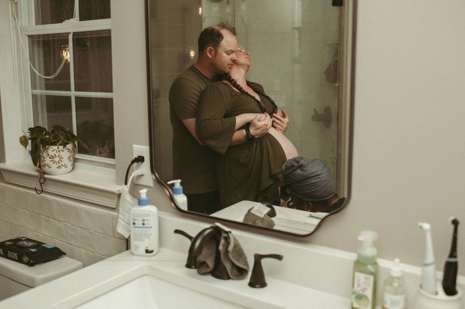 Mirror photo of a couple pushing through a contraction while a Hampton Roads midwife student checks babies heart rate.