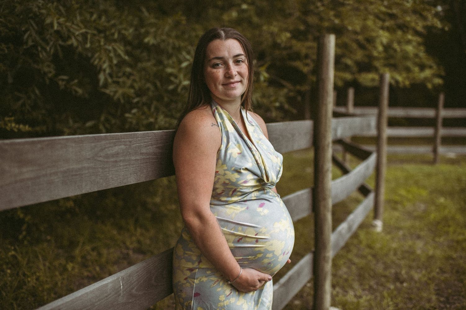 Expecting Franklin, VA mother posing during her maternity session while leaning on a wooden fence.
