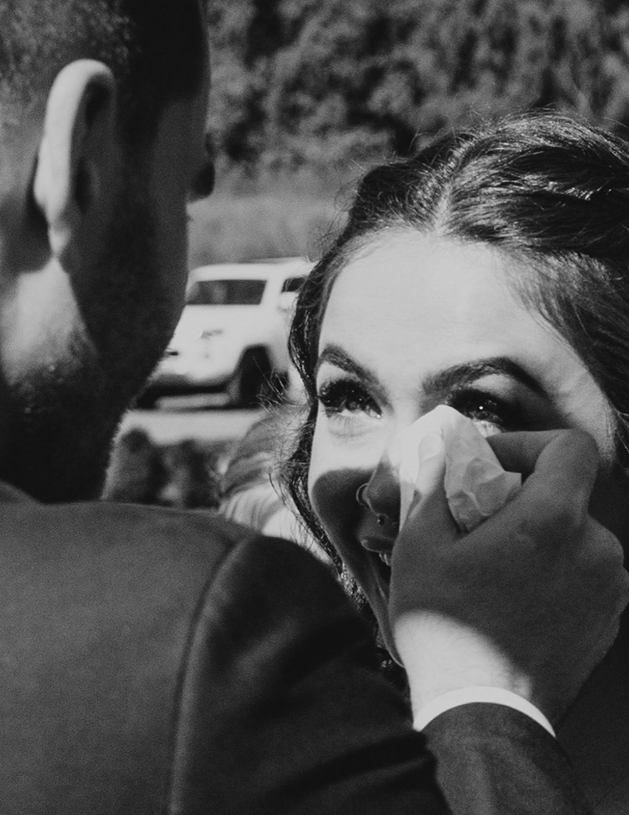 A bride eyes full of happy tears while her groom wipes them away with a tissue on the altar of their Vancouver wedding.