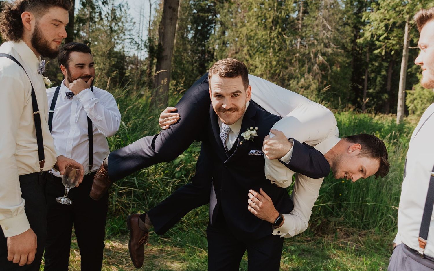 A groom playfully carrying his best mad across his back during his wedding party photos at his Vancouver wedding.