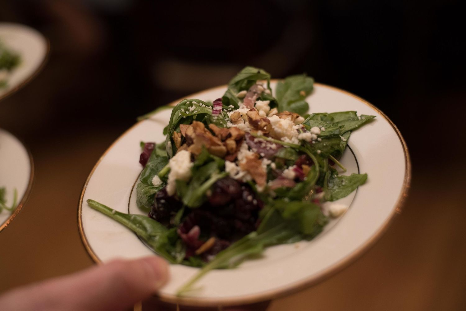 Fresh spinach salad topped with roasted beets, crumbled feta cheese, and walnuts served on a white plate.