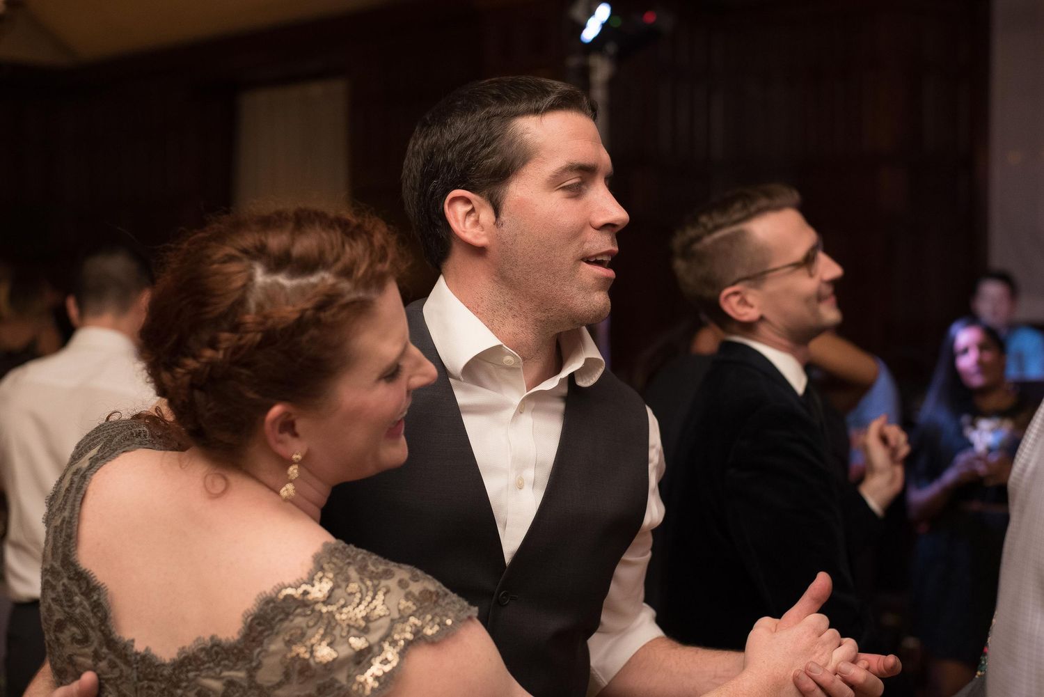 Couple dancing elegantly at a formal wedding reception in a dimly lit ballroom.