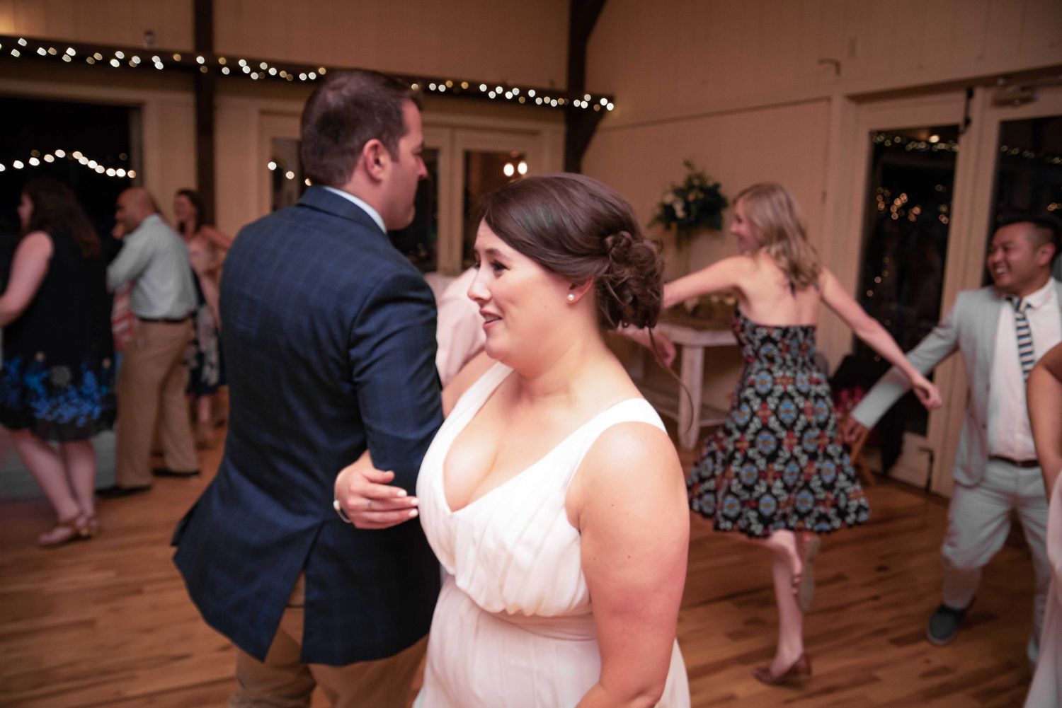 Bride and groom share a romantic dance at their wedding reception surrounded by guests on the dance floor.