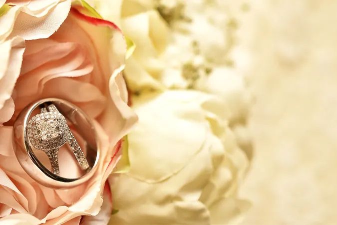 Diamond wedding ring nestled inside a pink rose in a bridal bouquet.