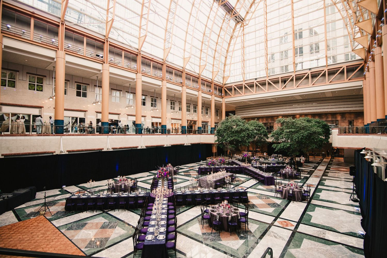Elegant wedding reception in grand atrium with ornate glass ceiling.