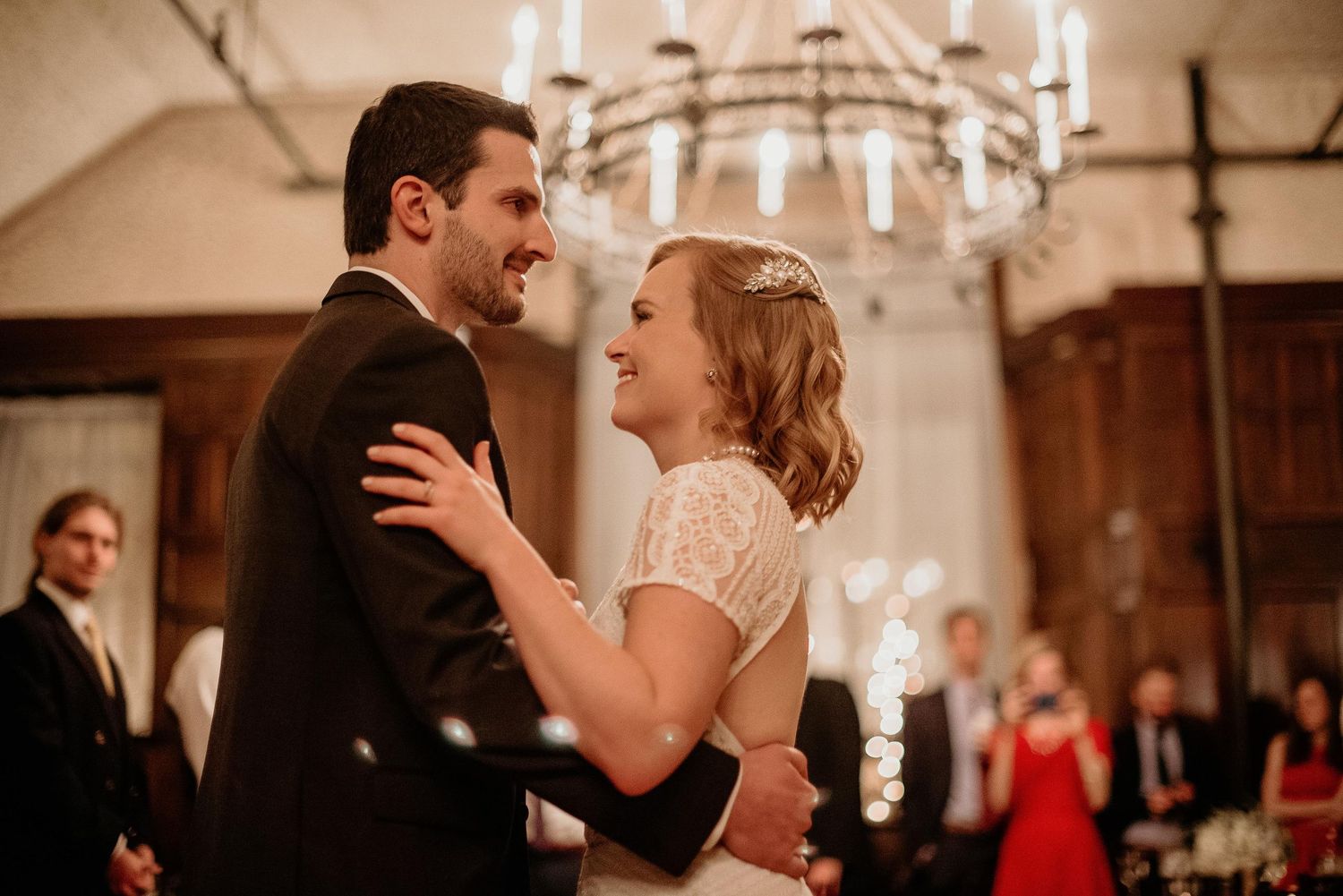 Bride and groom share their first dance under a chandelier in an elegant wedding venue.