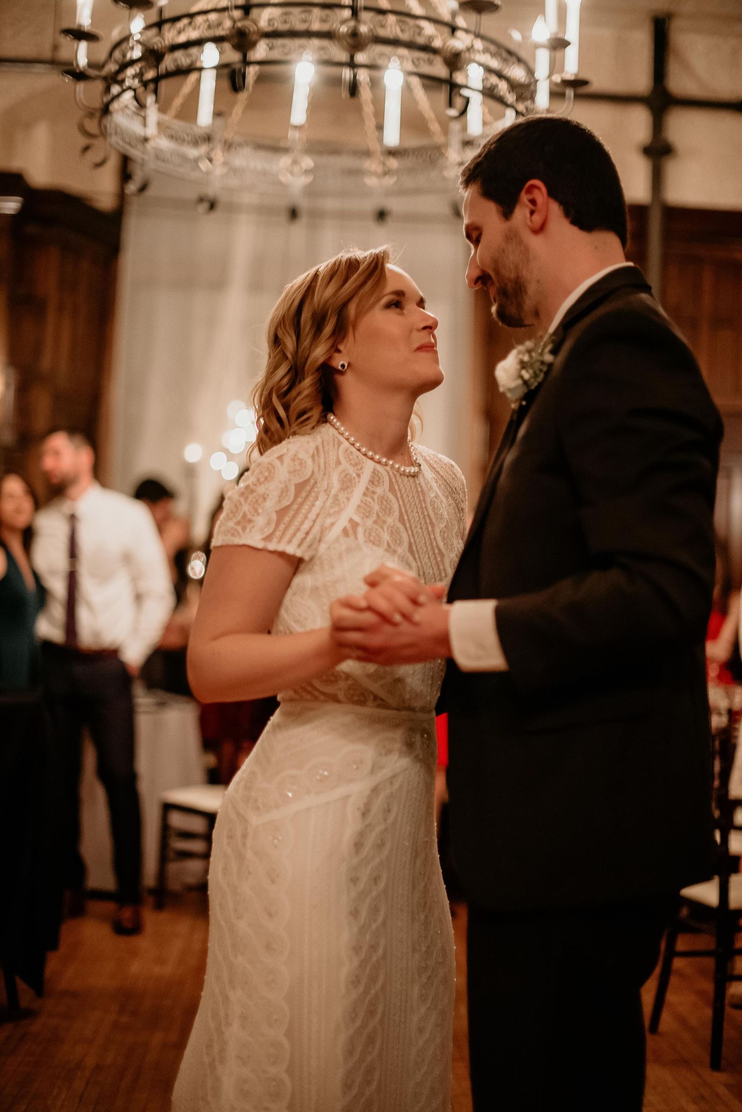 Bride and groom share their first dance under a chandelier at their elegant wedding reception.