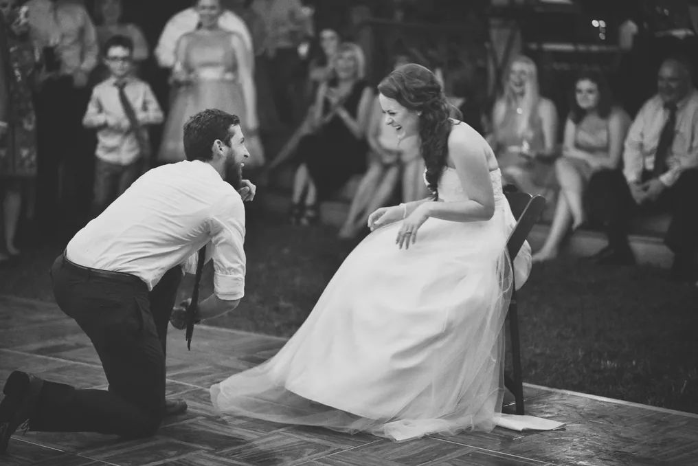 Black and white photo of bride and groom sharing a playful moment during their outdoor wedding reception dance.