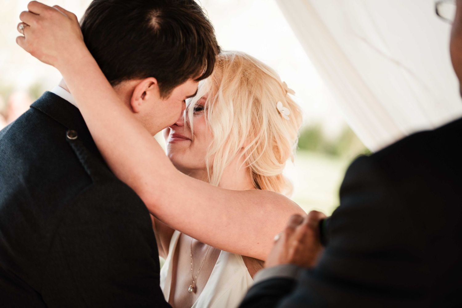 Couple sharing a romantic first dance embrace at their wedding reception under a white tent.