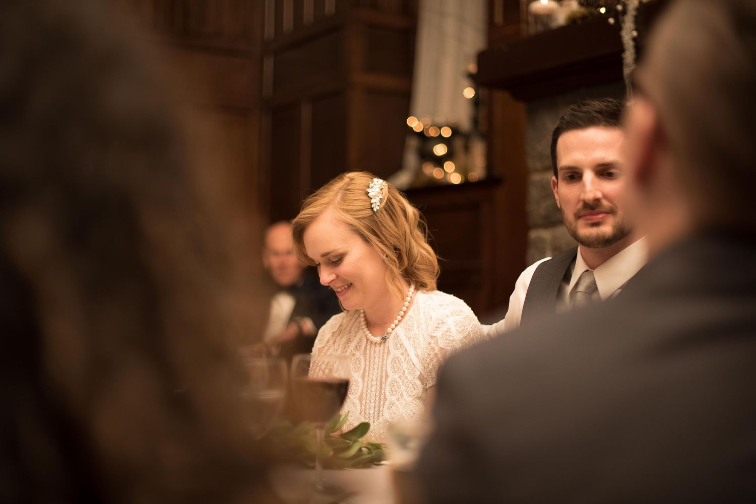 A smiling bride and groom sit together at their wedding reception dinner table.