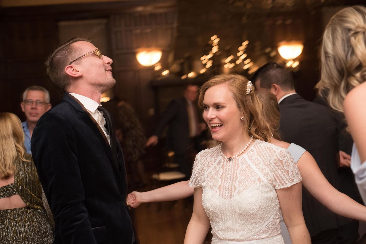 Couple laughing and dancing joyfully at a wedding reception in an elegant venue.