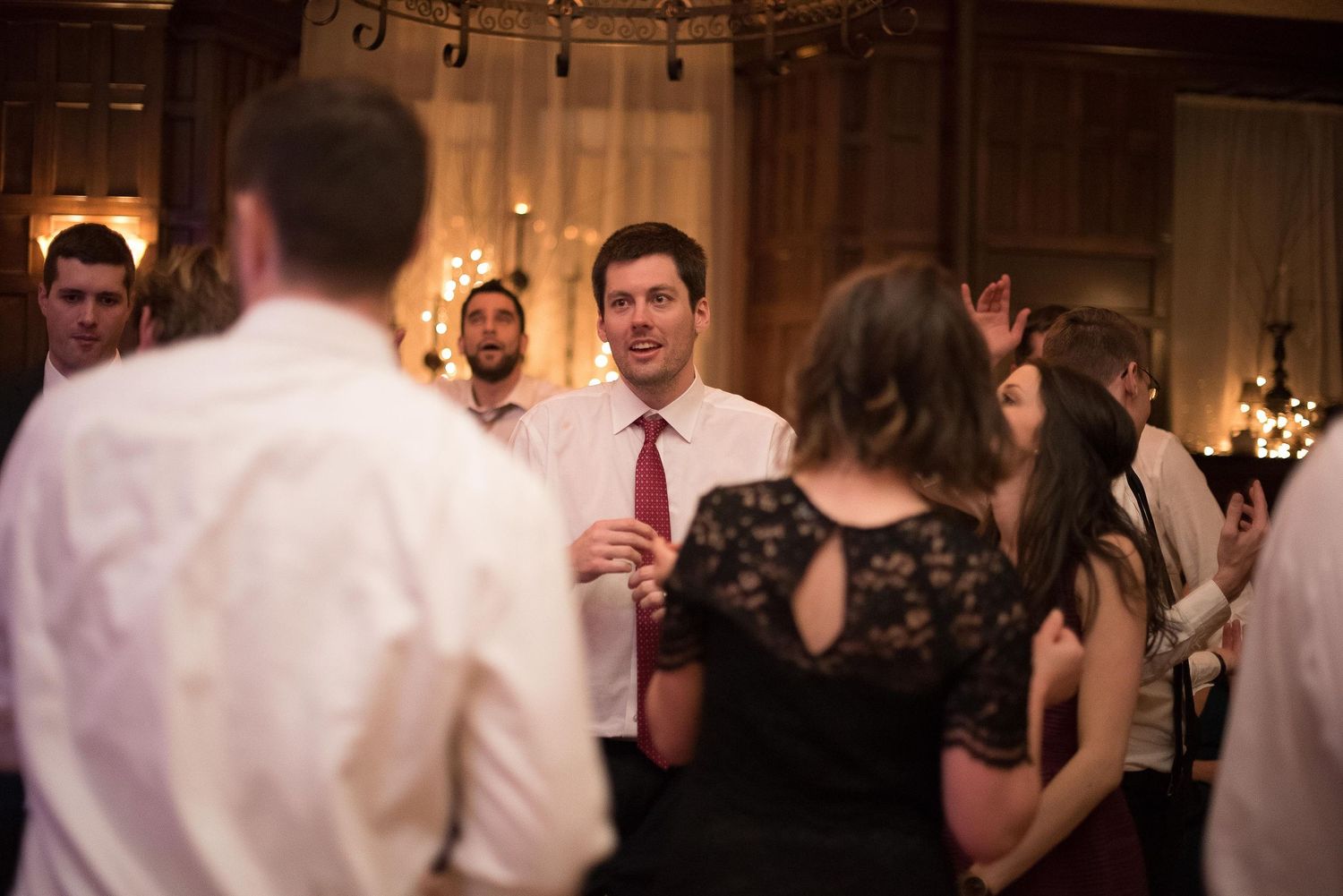 Guests dancing and socializing at an elegant wedding reception in a warmly lit venue.