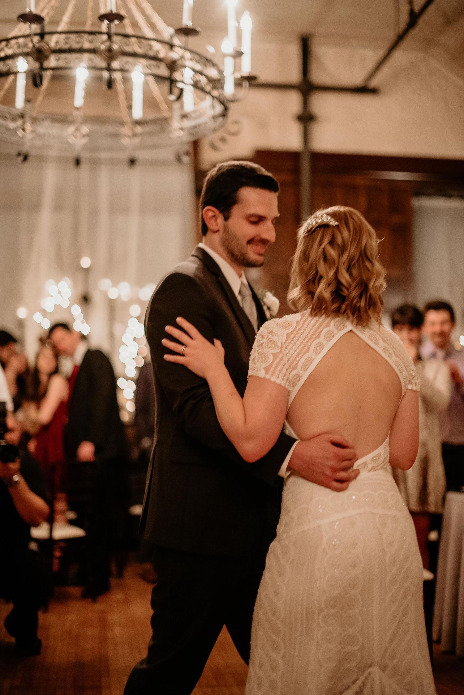 Bride and groom share their first dance under a chandelier at an elegant wedding reception.