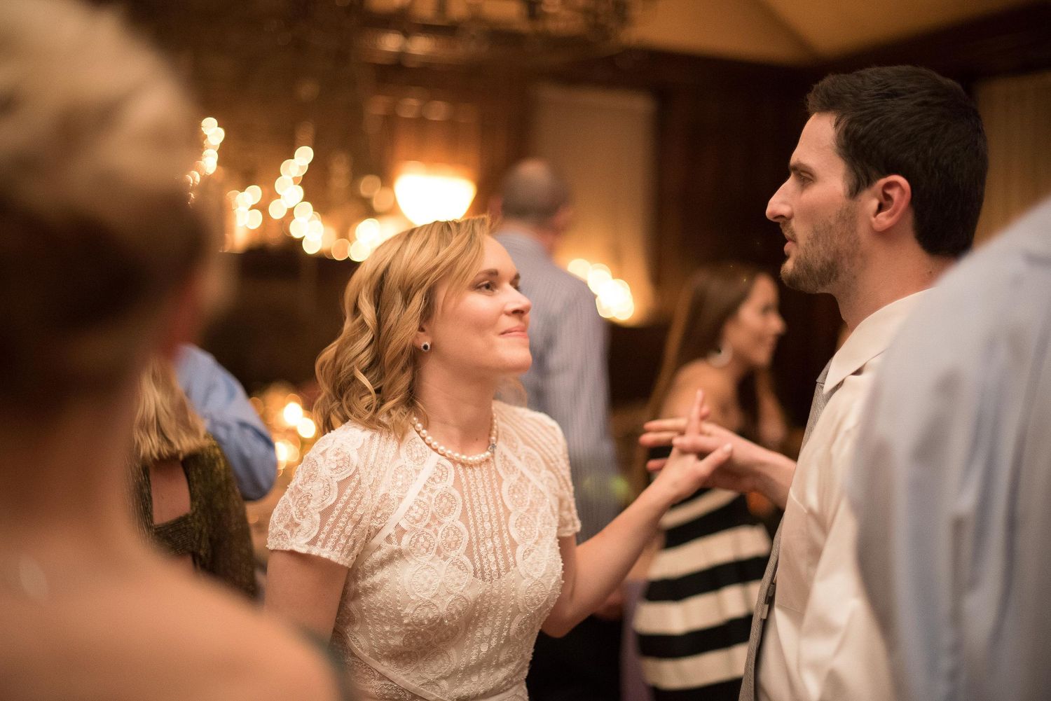 Couple sharing a romantic moment dancing at an elegant wedding reception with warm glowing lights in background.
