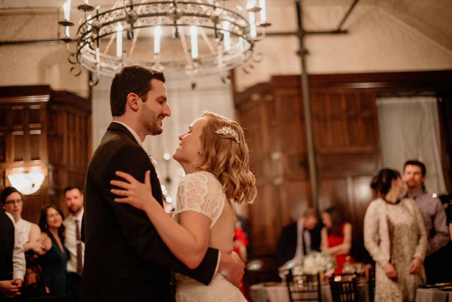Bride and groom share their first dance under a chandelier at an elegant wedding reception.