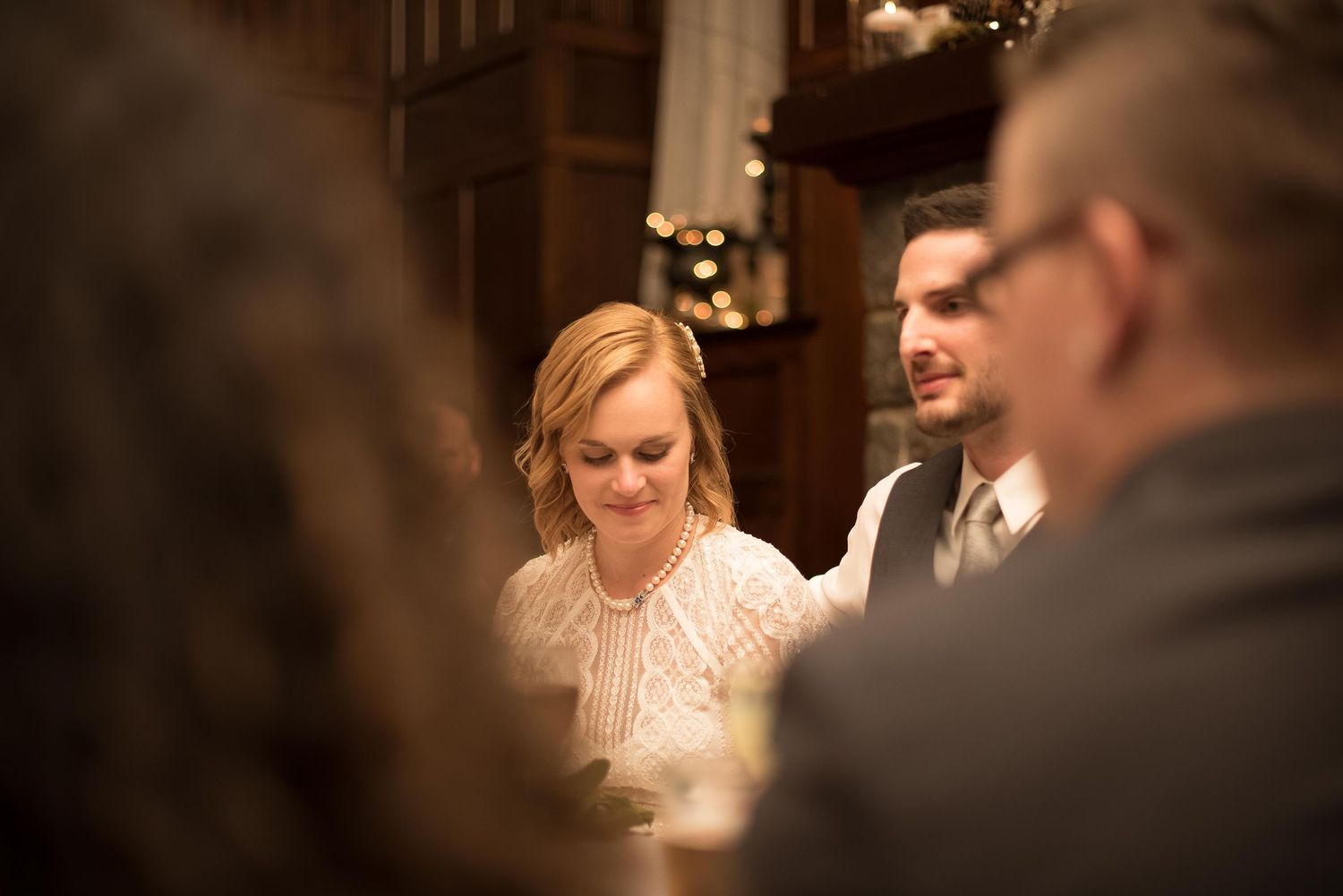 Bride and groom share a quiet moment together at their elegant wedding reception with warm bokeh lights.