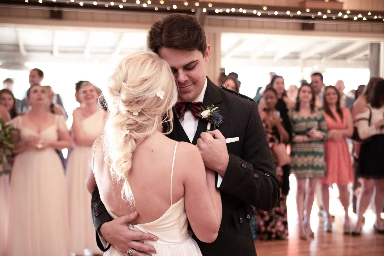 Bride and groom share their first dance at wedding reception, surrounded by guests in formal attire.