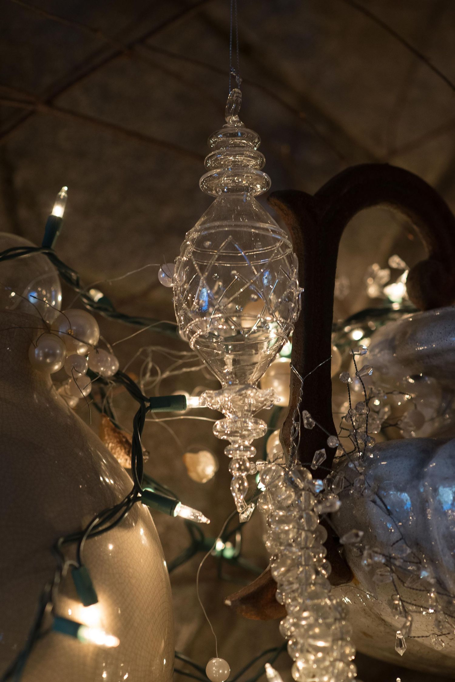 Crystal glass ornament hanging amidst glowing white Christmas lights in a festive holiday display.