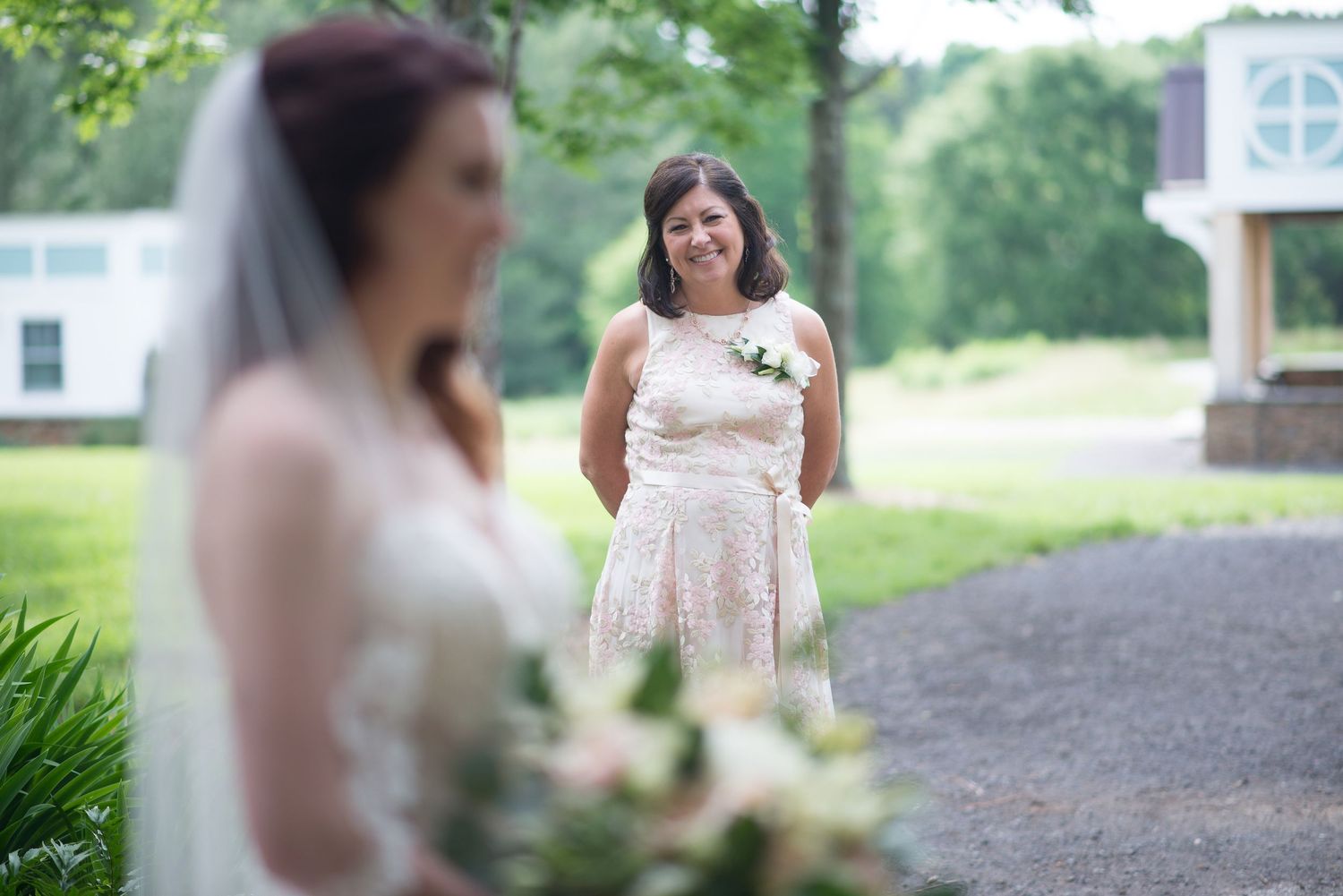 Mother emotionally watching her daughter in wedding dress during an outdoor first look.