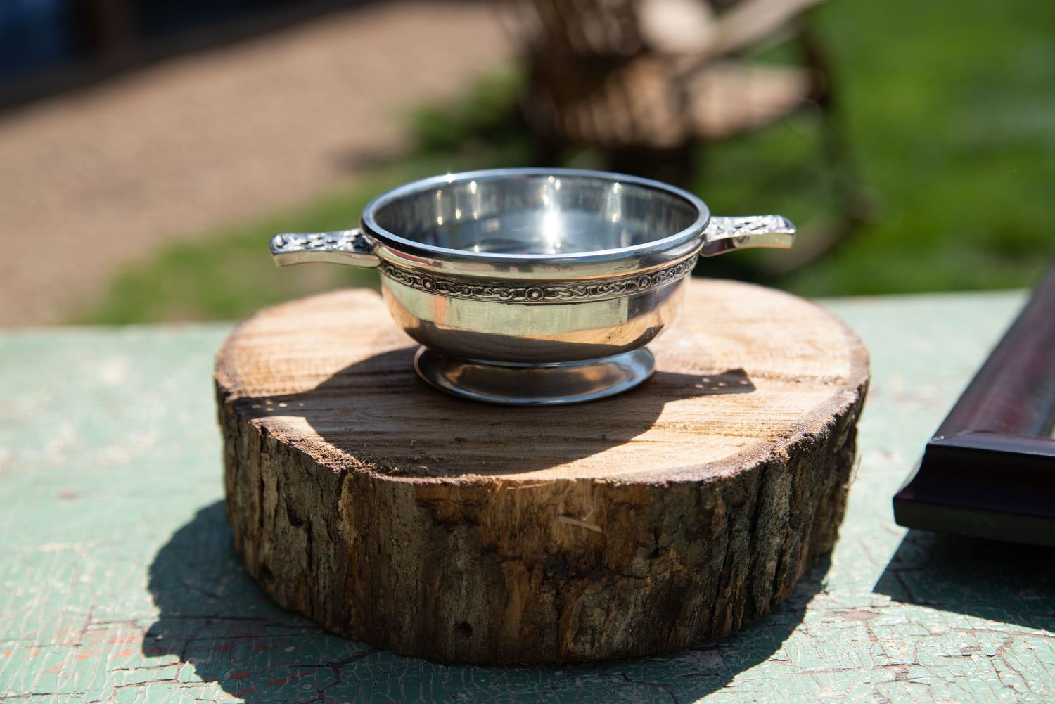 Traditional Scottish silver quaich loving cup displayed on a wooden log slice at a wedding ceremony.