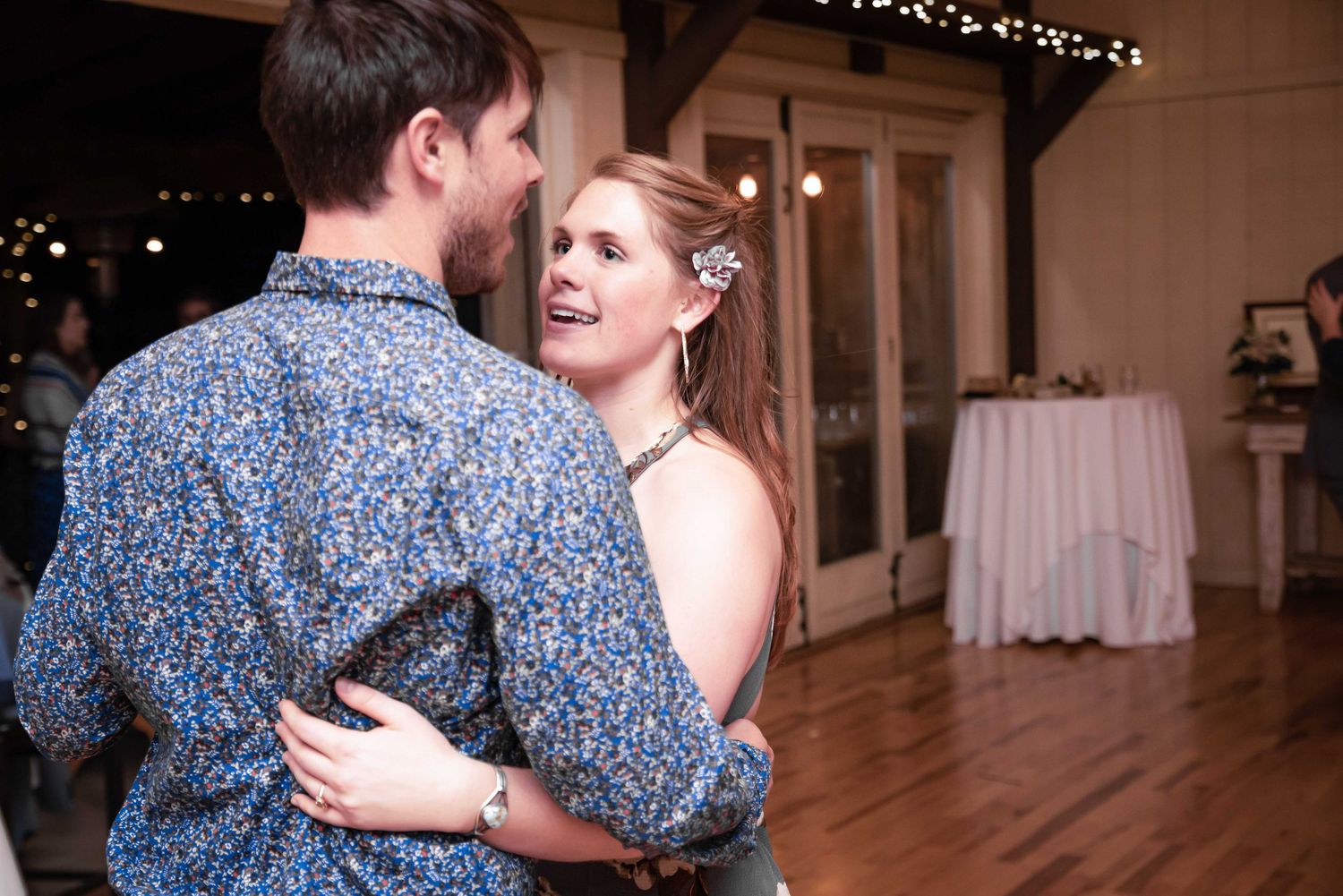 Couple sharing a romantic first dance at a wedding reception in a warmly lit rustic venue.