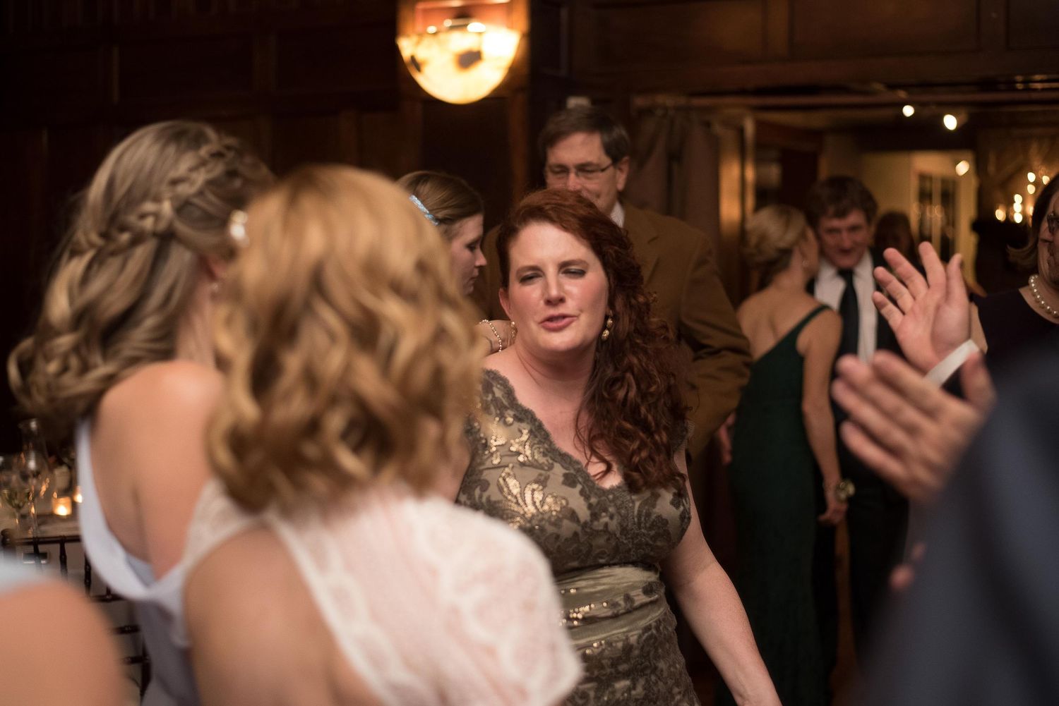 Guests dancing and socializing at an elegant indoor wedding reception in a warmly lit venue.