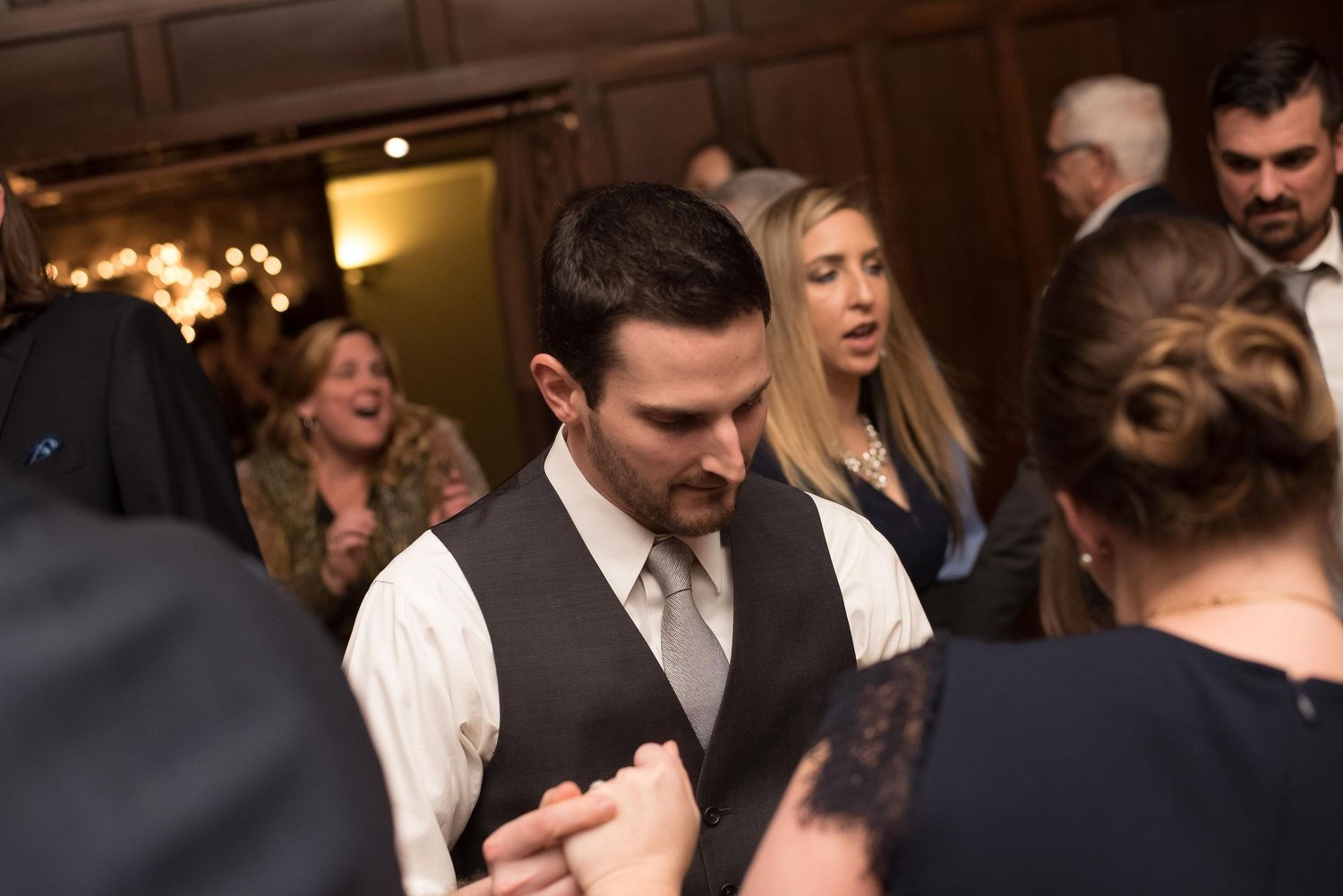 Guests dancing and socializing at an elegant indoor wedding reception in a warmly lit venue.