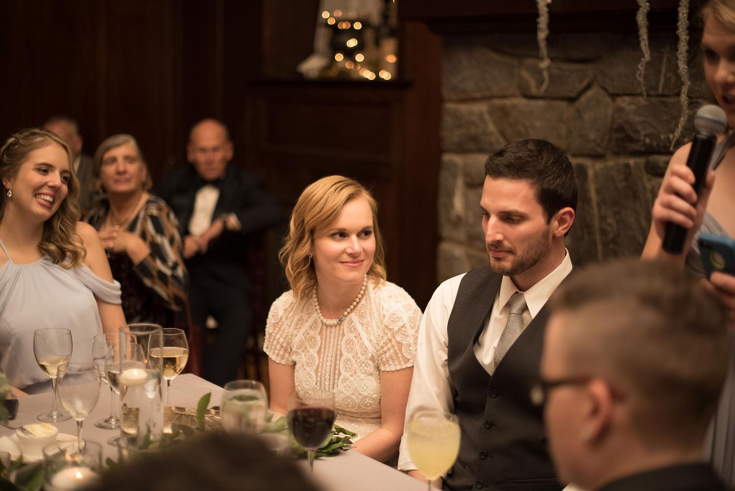 Guests smiling and laughing during wedding reception speeches at an elegant stone venue.