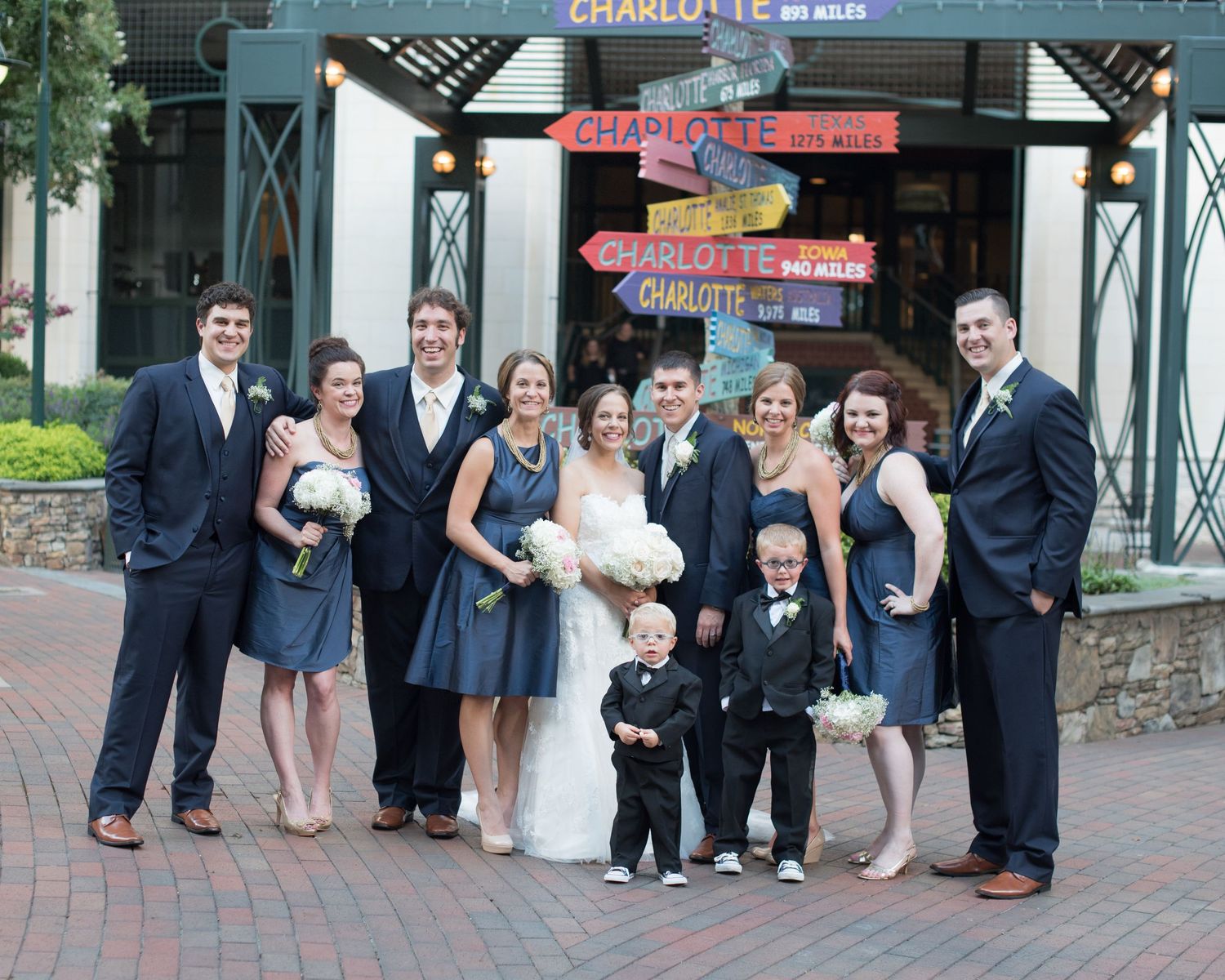 Wedding party posing outdoors in navy attire near Charlotte city signs.