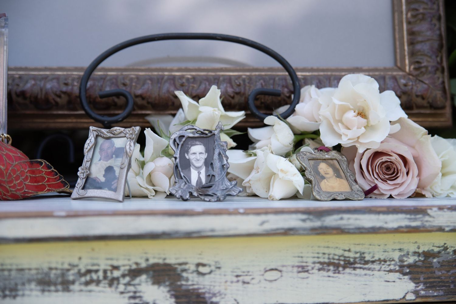 Vintage wedding memorial display with framed photos of loved ones surrounded by white and blush roses.