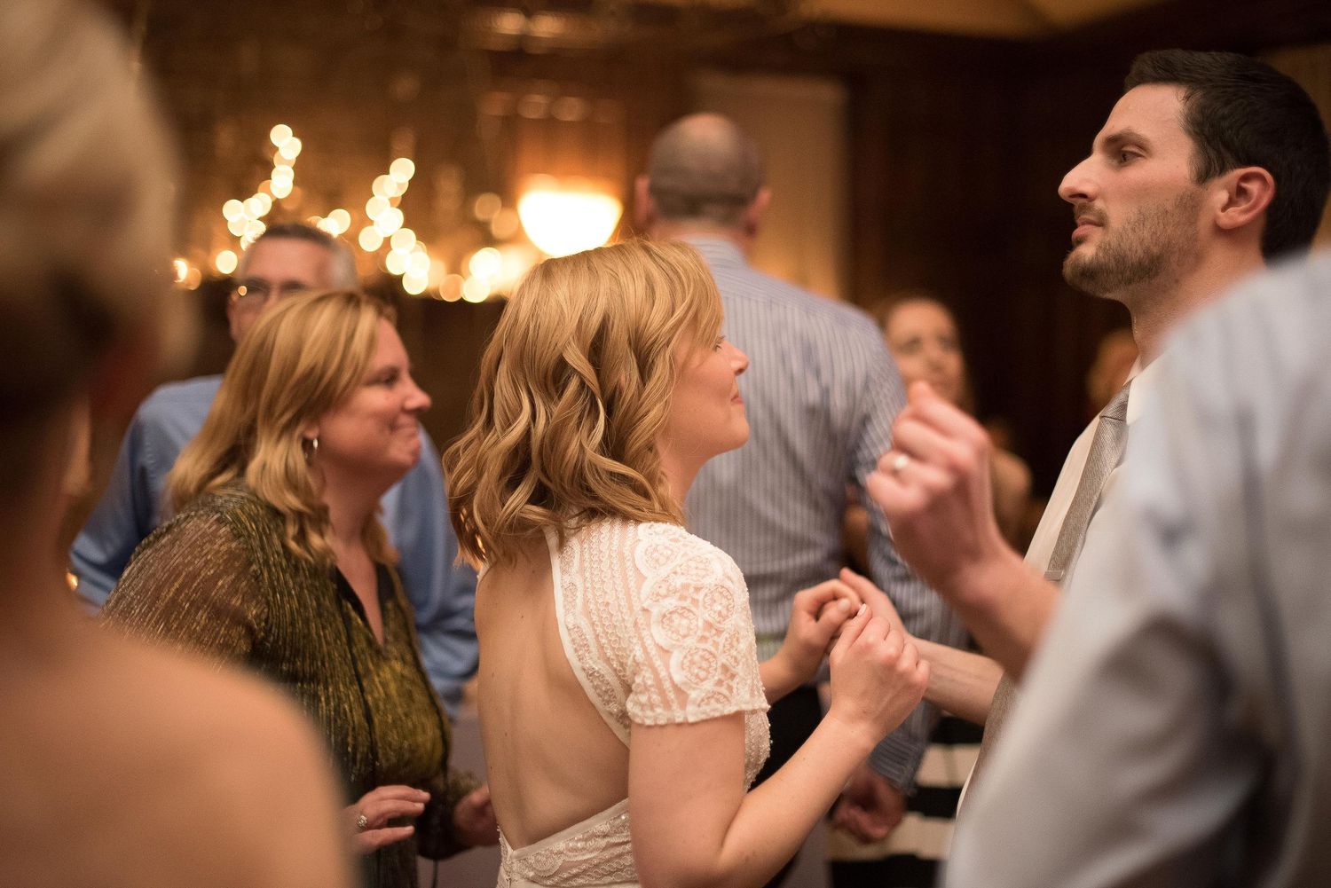 Guests dancing and socializing at an elegant indoor wedding reception with warm ambient lighting.