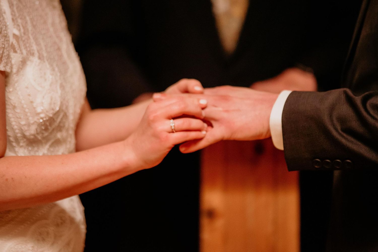 Bride and groom exchanging wedding rings during marriage ceremony, close-up of hands.