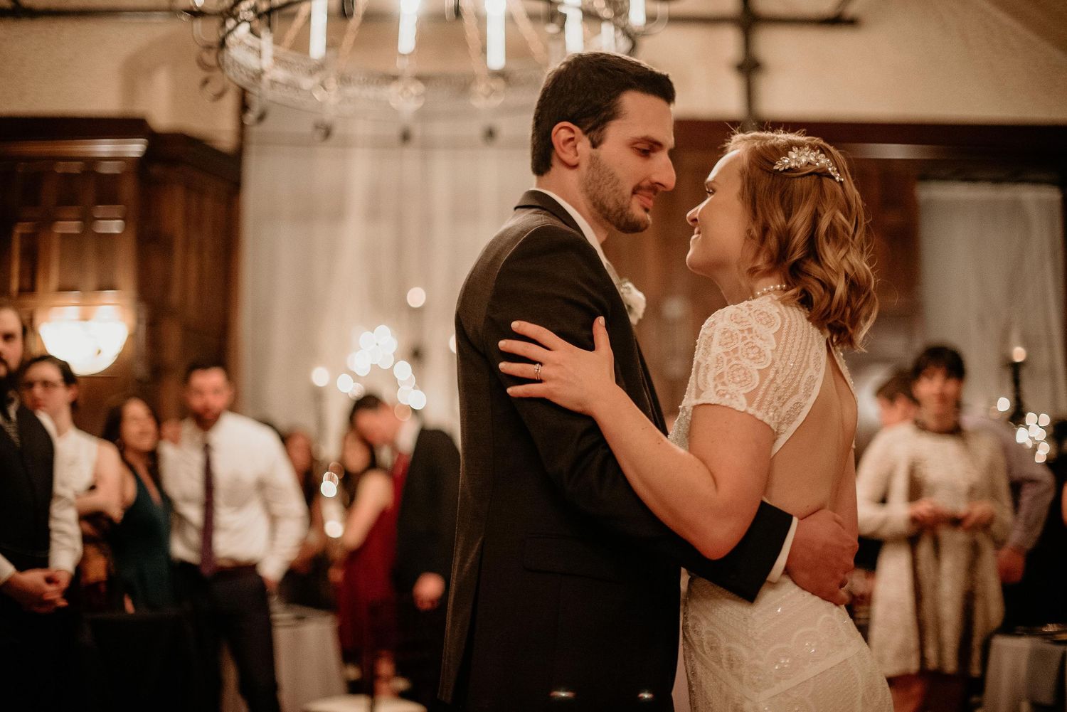 Bride and groom share their first dance surrounded by guests holding sparklers at elegant wedding reception.