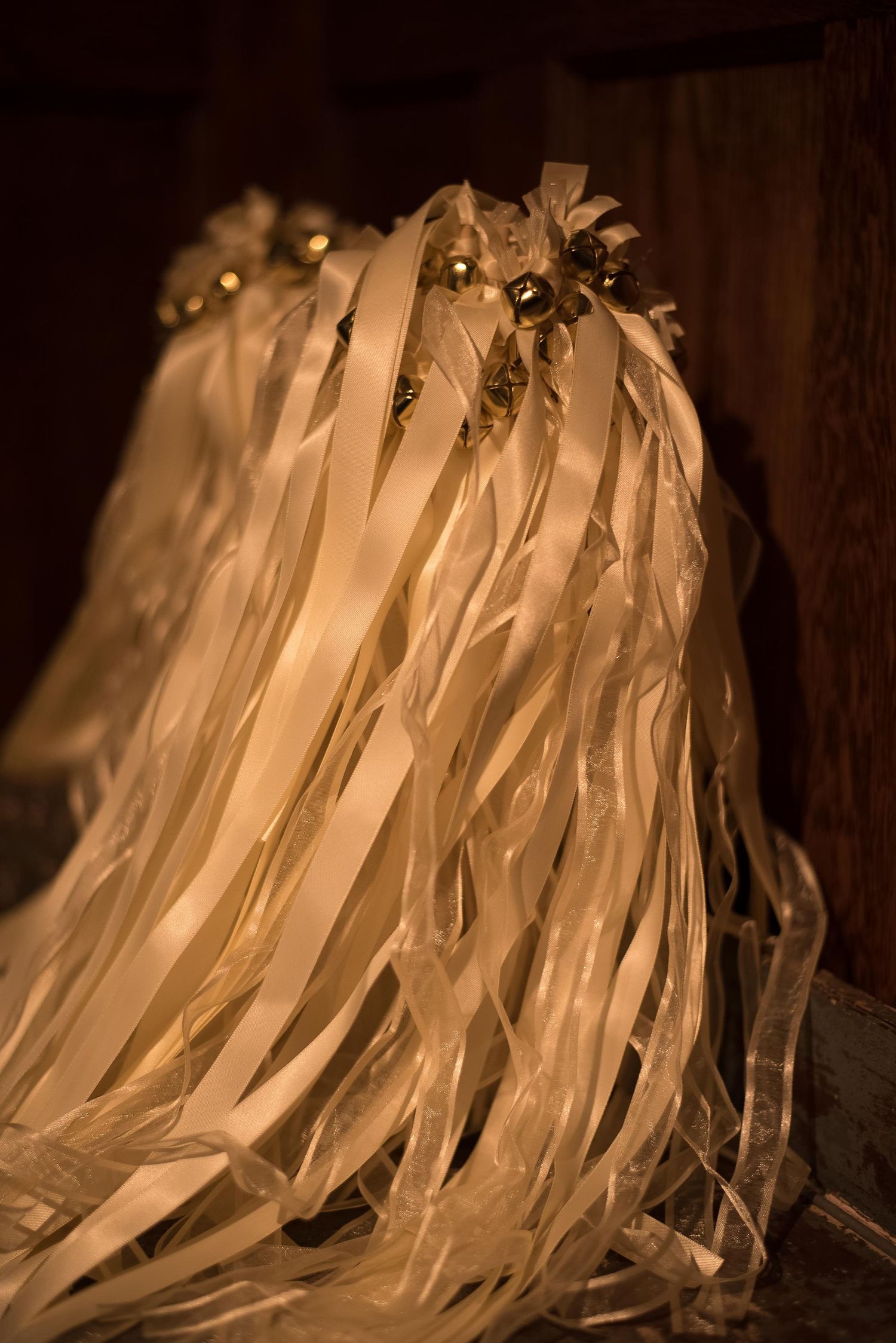 Elegant cream ribbon wands with gold floral accents glowing in warm light, perfect for weddings or celebrations.